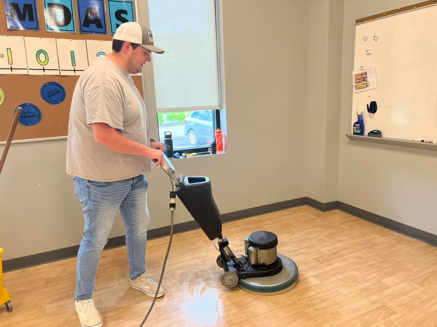 A Truly, Truly Clean team member operating a floor buffer in a classroom
