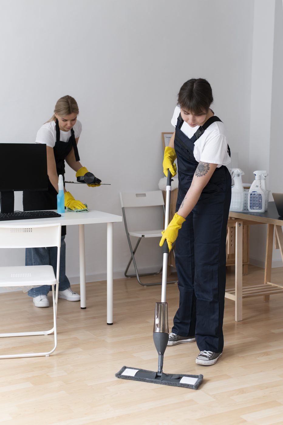 Two Truly, Truly Clean team members cleaning desks and floors in an office