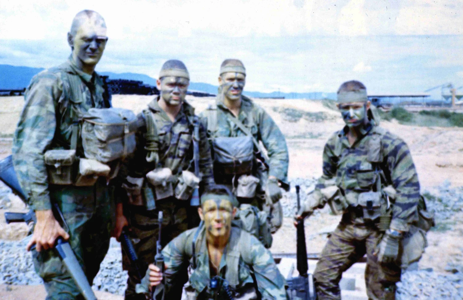 Archival photo of five service members in camouflage uniforms and face paint